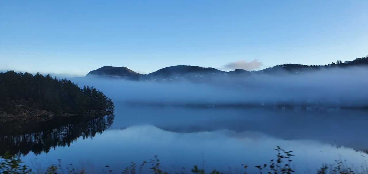 Misty mountains reflected in a calm lake at dawn