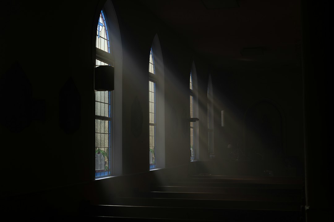 Dimly lit corridor with shadows casting eerie patterns, evoking a sense of suspense and isolation.