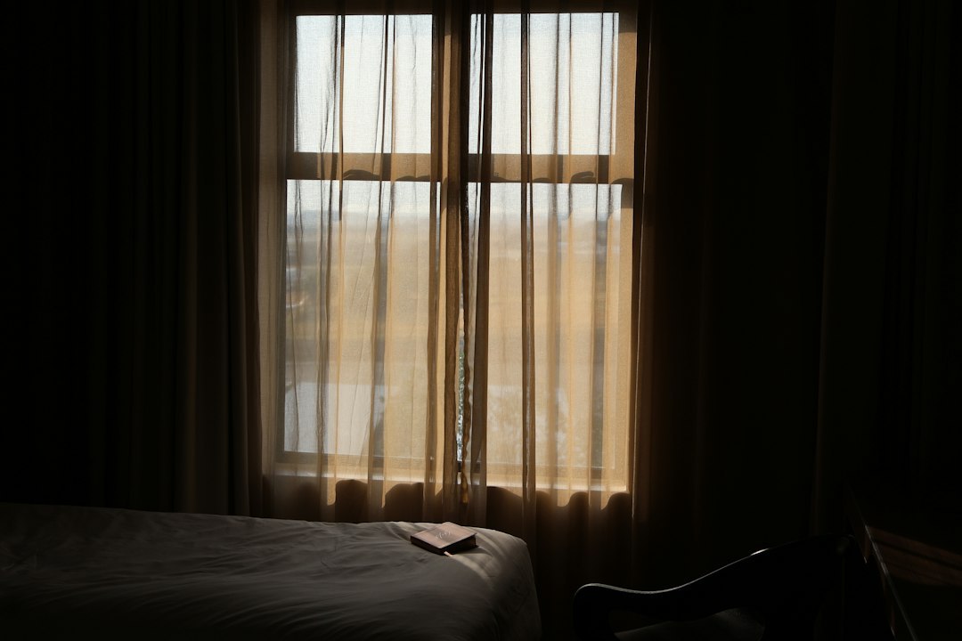 Sunlight filters through sheer curtains in a dim room